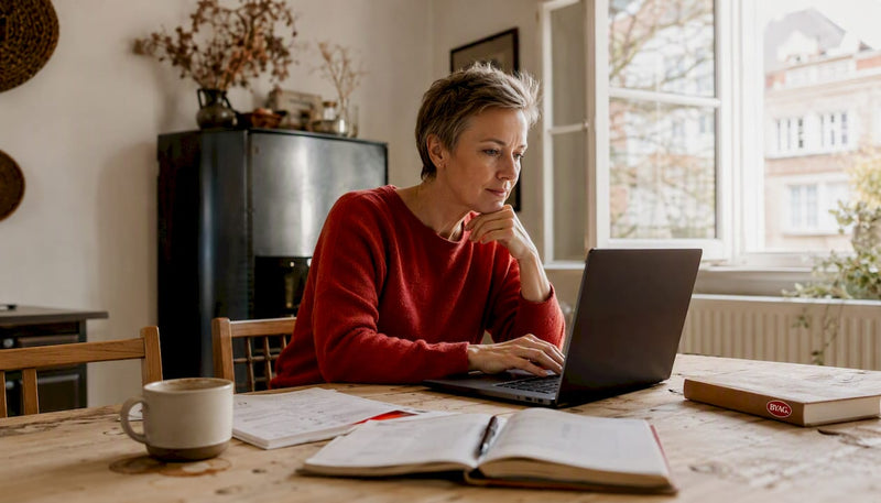 Eine Frau sitzt entspannt zu Hause und vergleicht verschiedene Online-Marktplätze, um das beste Angebot zu finden.